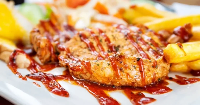 Outback Steakhouse Alice Springs Chicken served with a drizzle of barbecue sauce, golden fries, and fresh vegetables on the side.